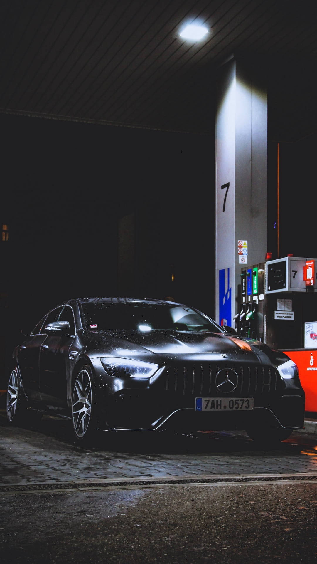 梅賽德斯在加油站 壁紙 — 一輛時尚的黑色Mercedes-AMG在夜間停放在一個明亮燈光下的加油站油泵旁。