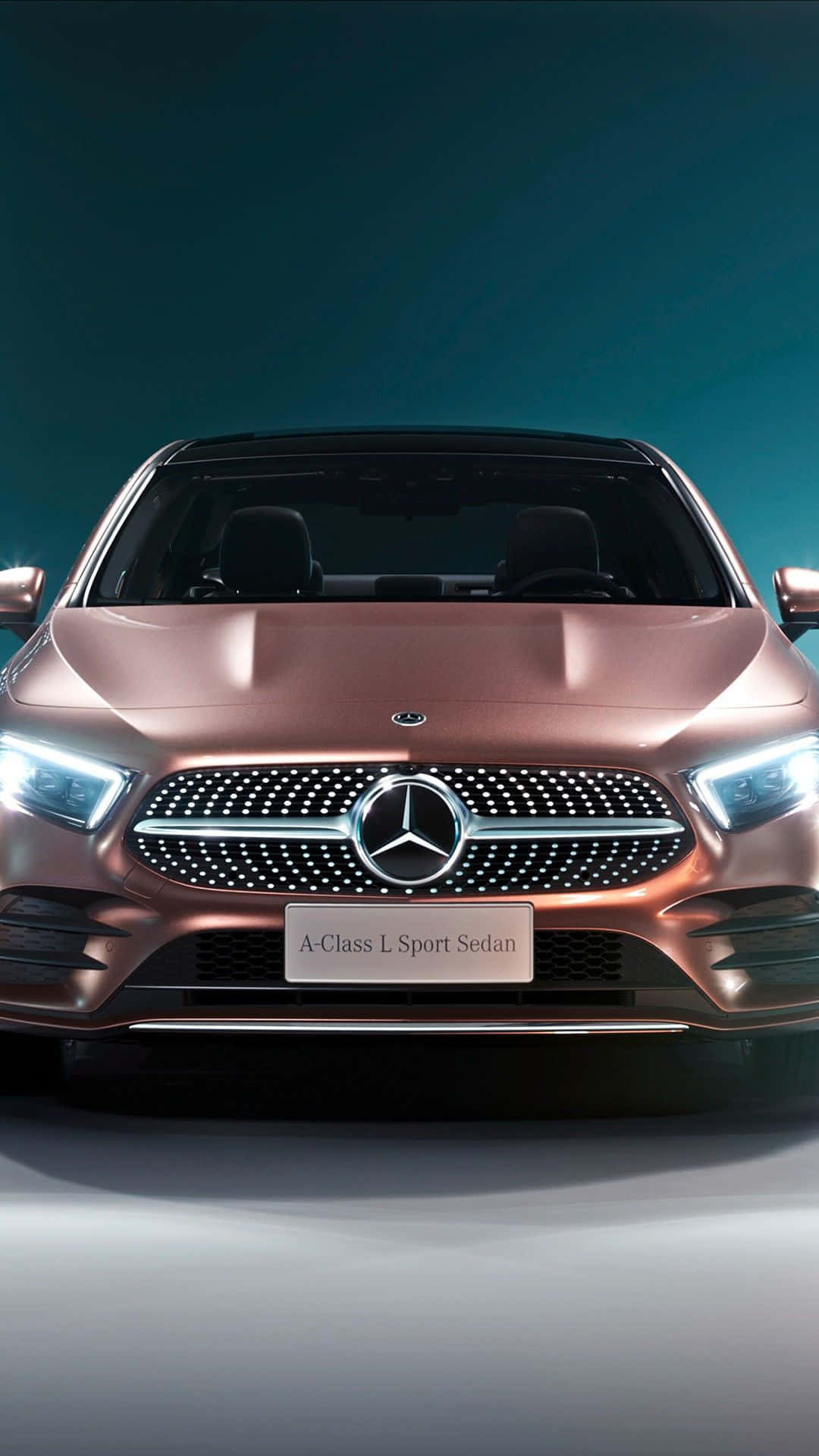 玫瑰金色平治A-Class L Sport Sedan在攝影棚燈光下的正面視圖。