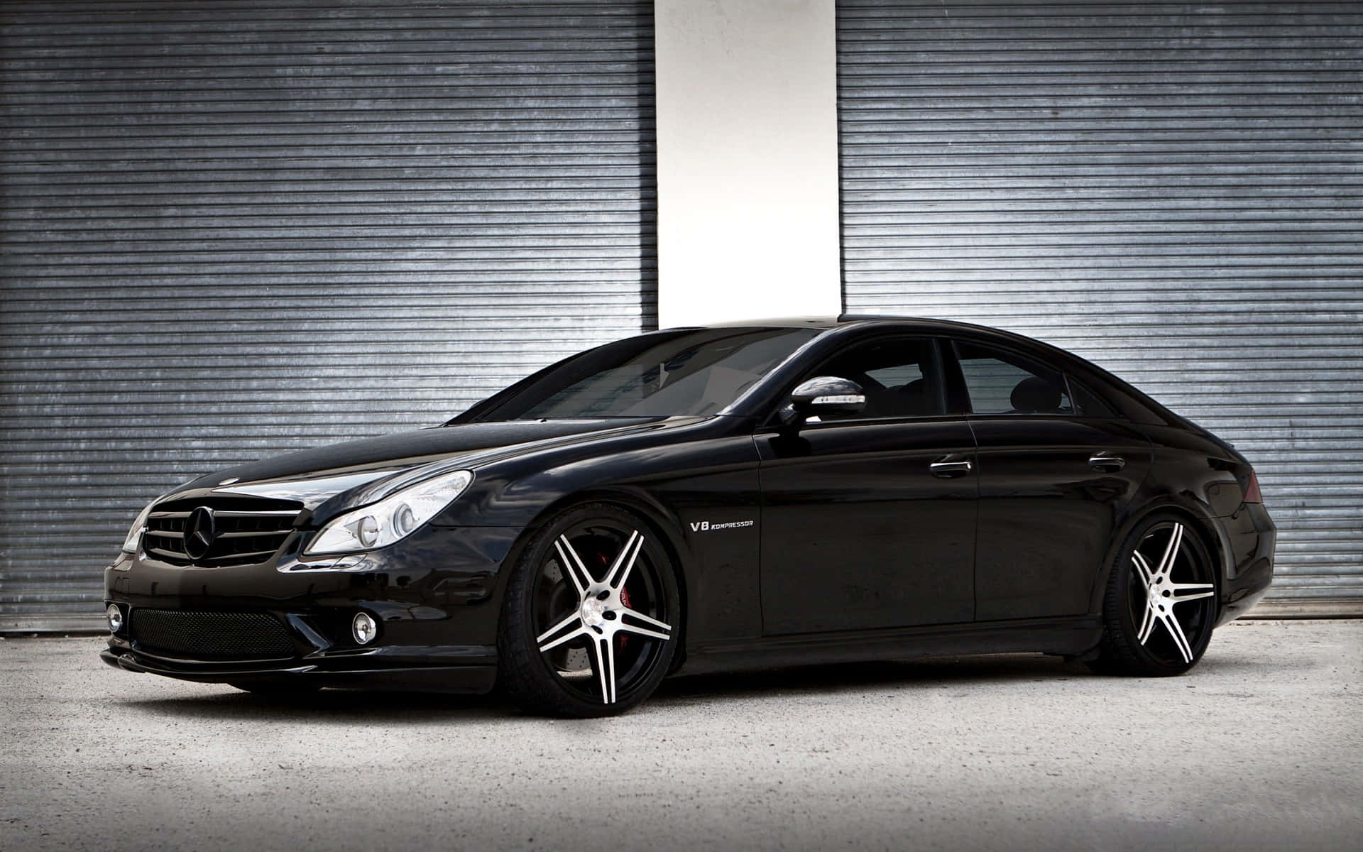 黑色Mercedes-Benz CLS63 AMG配銀色輪圈，停在金屬車庫門前。