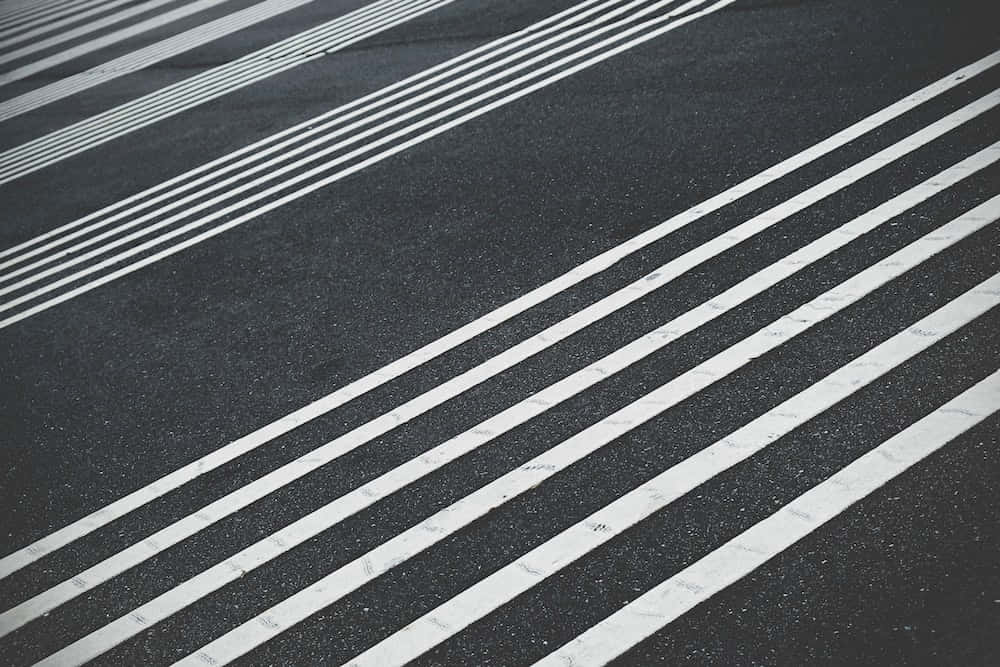 條紋混凝土道路圖 壁紙 — 對角白色條紋以銳利幾何圖案切割深色瀝青路面。