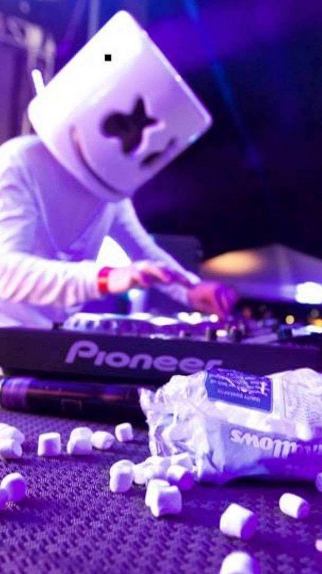 DJ Marshmello 喺紫色燈光同枱上嘅棉花糖下表演緊。