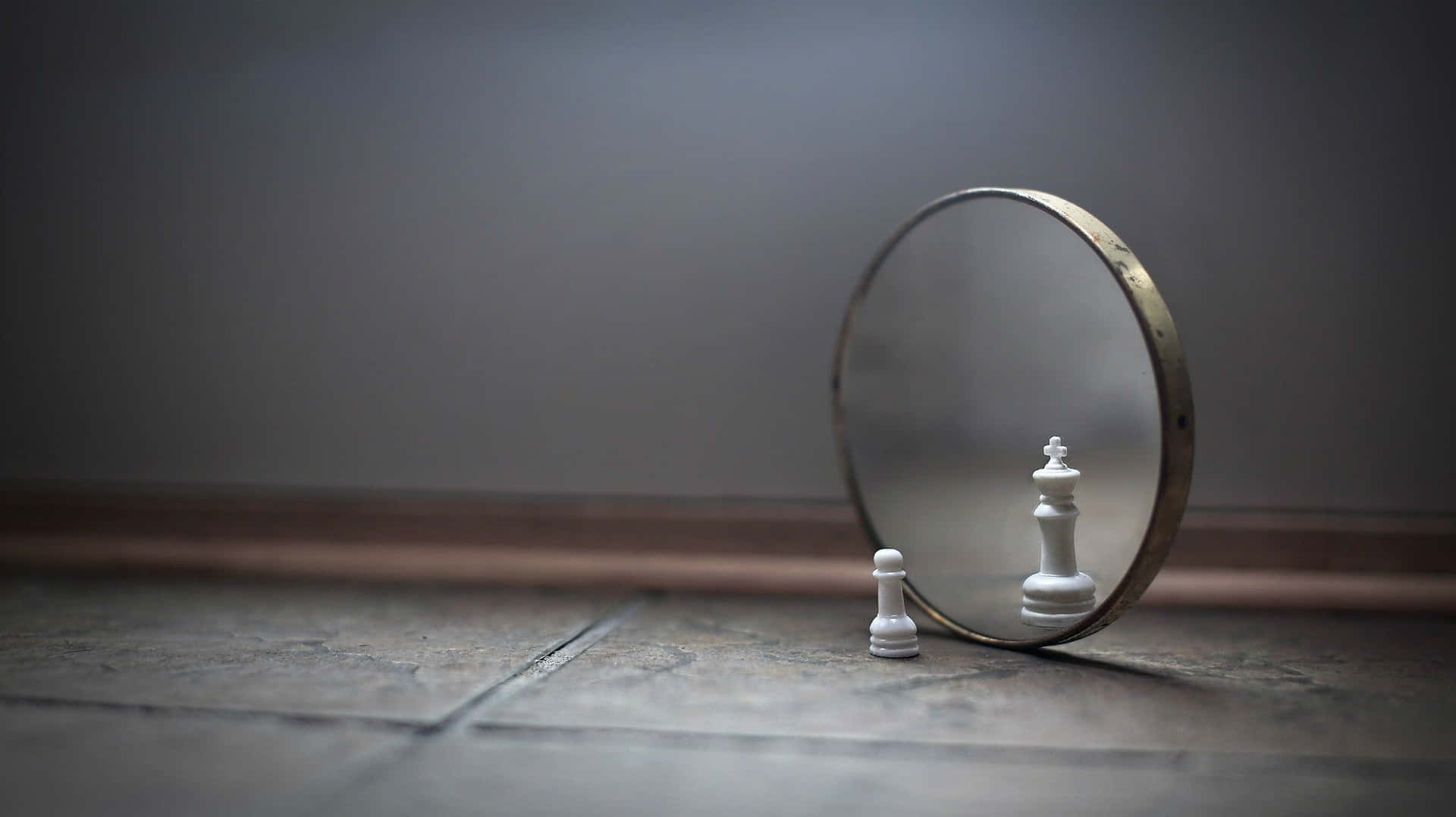 一個國際象棋兵喺一個鏡前面，鏡子反射出一個國際象棋國王喺瓷磚地板上。