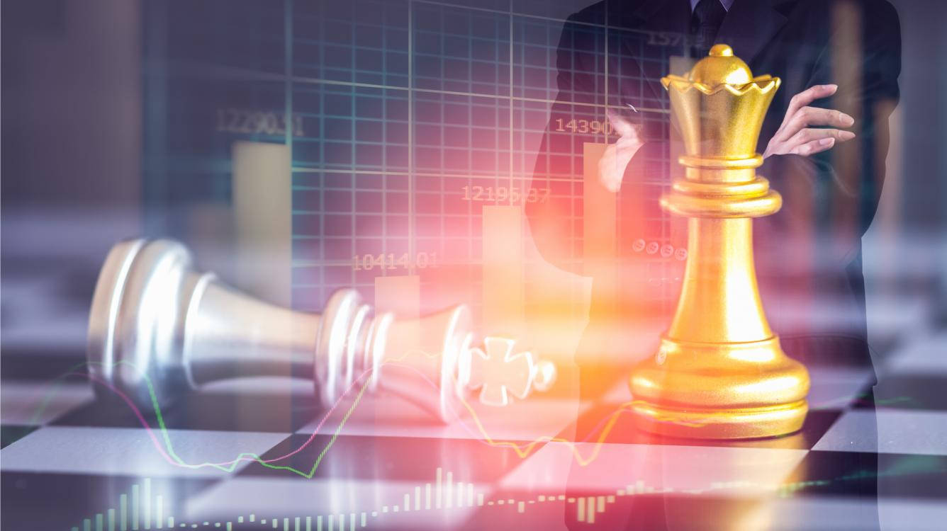 棋局商戰：銀色國王與金色皇后 壁紙 — 金色國際象棋國王在疊加發光金融圖表的棋盤上，勝利地站在倒下的銀色棋子之上。