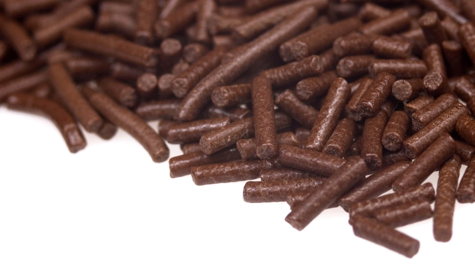 Brown Chocolate 桌布 壁紙 — 棕色圓柱形寵物食品顆粒在純白背景上對角散落的特寫。