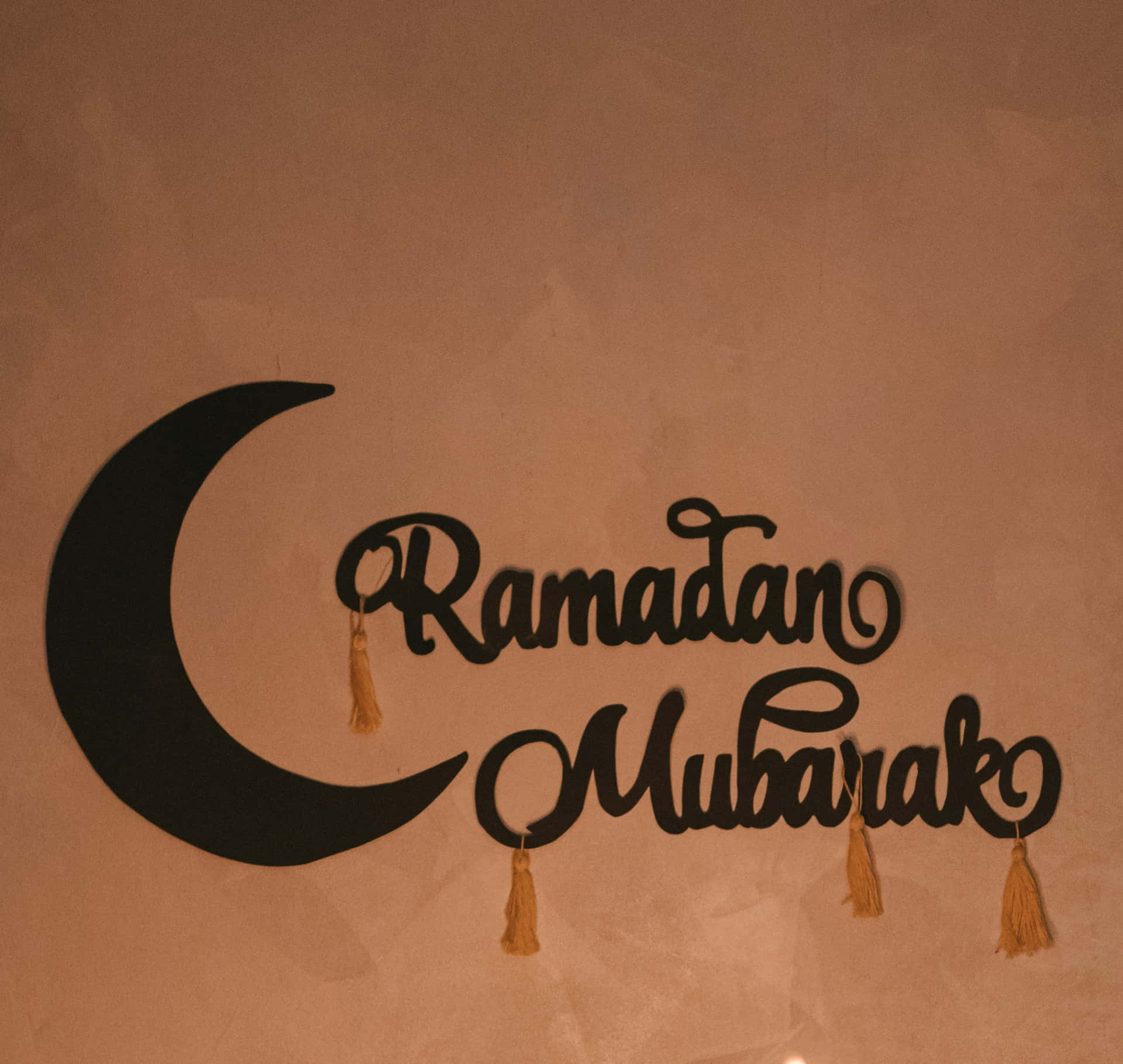帶有新月和流蘇的 Ramadan Mubarak 標誌掛在紋理牆上。