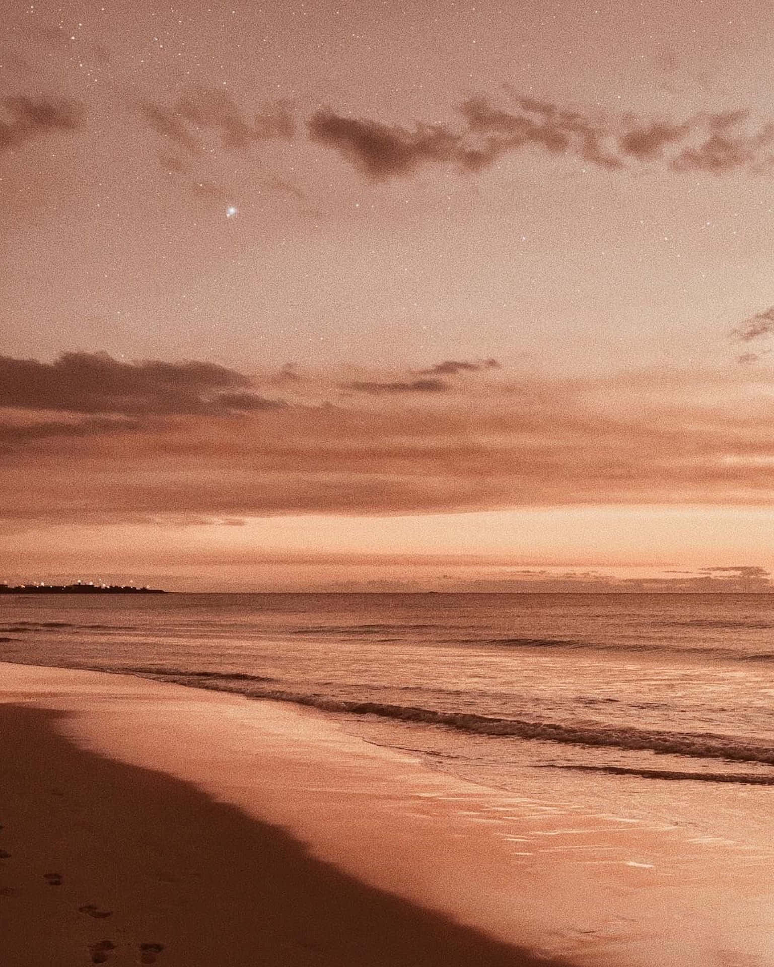星光閃爍的海灘，黃昏時溫柔的海浪和沙灘上的腳印。