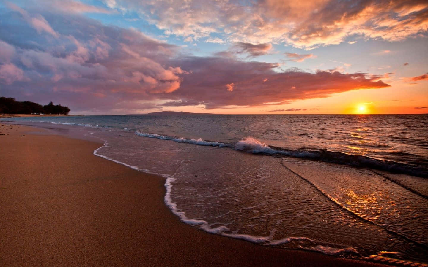 棕褐色沙灘日落桌面壁紙 壁紙 — 夕陽將天空染成火熱的橙色和粉紅色，海浪輕輕拍打著金色的沙灘。