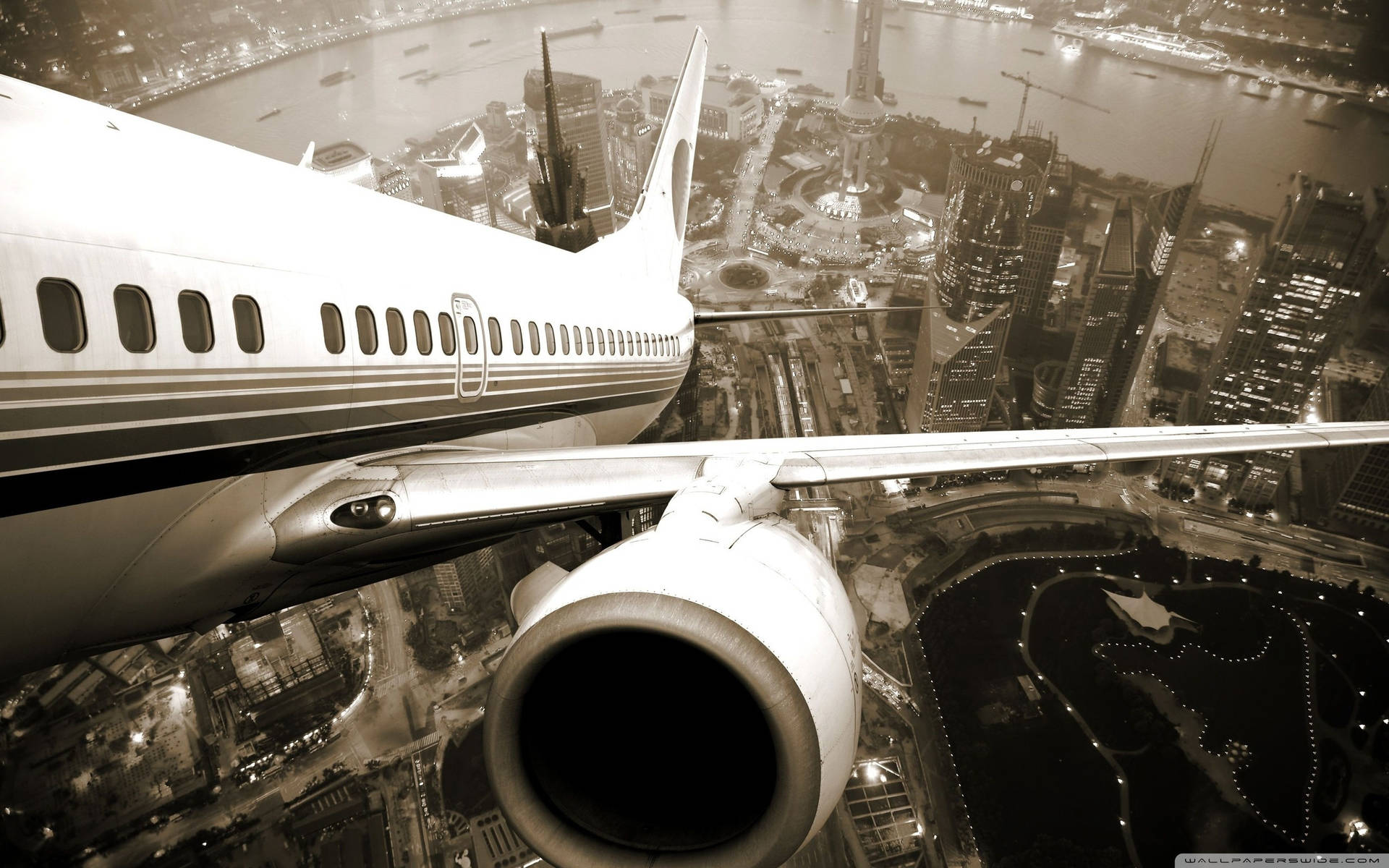 飛機機翼和引擎在夜間飛越發光的城市。
