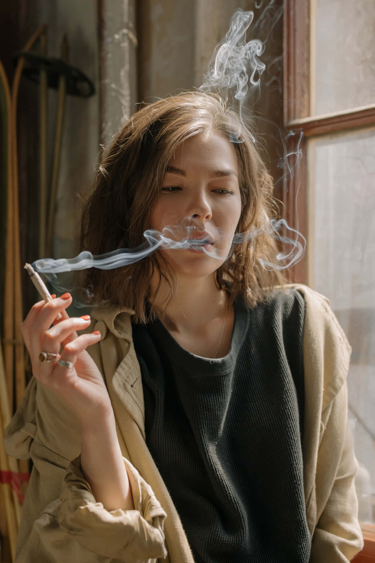 女性在室內窗邊吸煙，有陽光