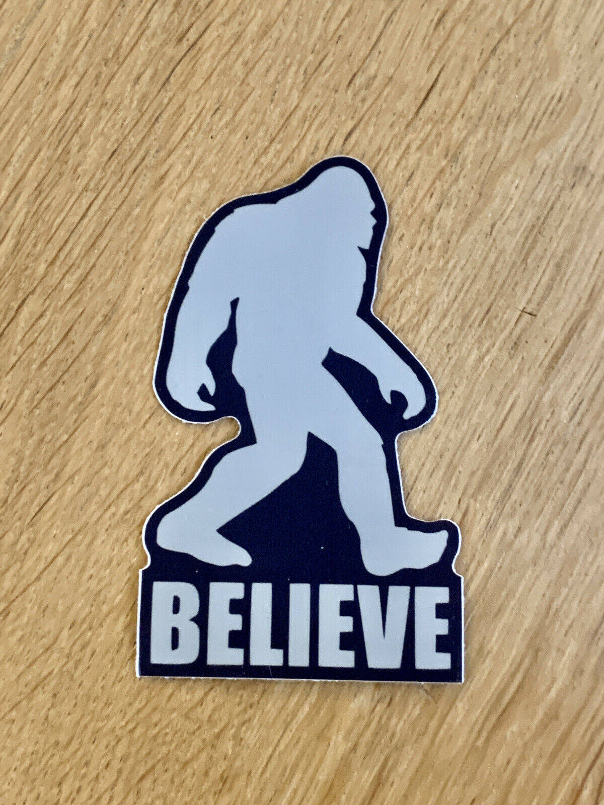 大腳怪剪影貼紙，上面有「BELIEVE」文字在木頭上。
