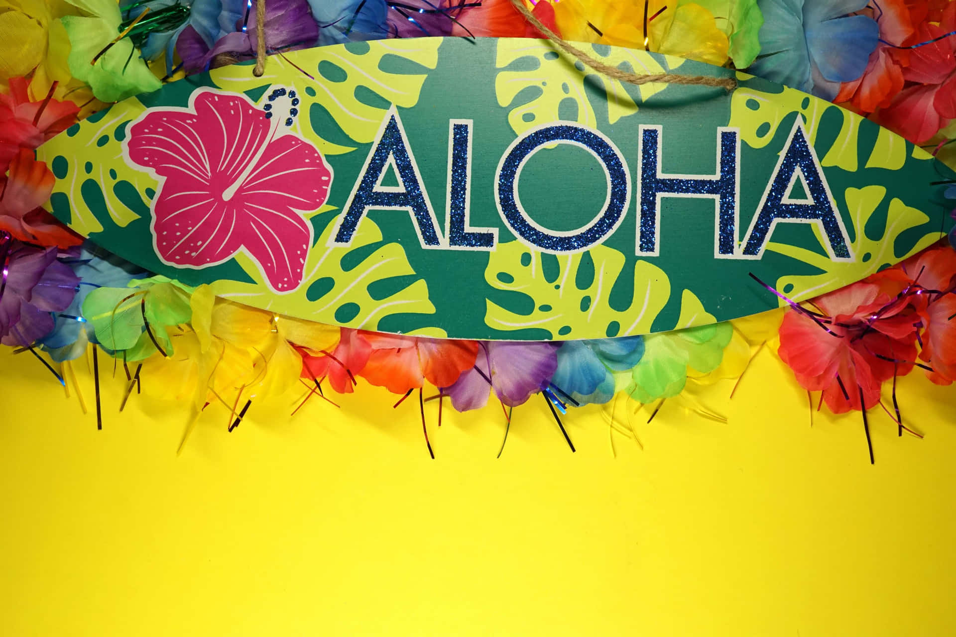 一個色彩繽紛的衝浪板標誌，帶有「ALOHA」和木槿花，周圍環繞著熱帶花卉。