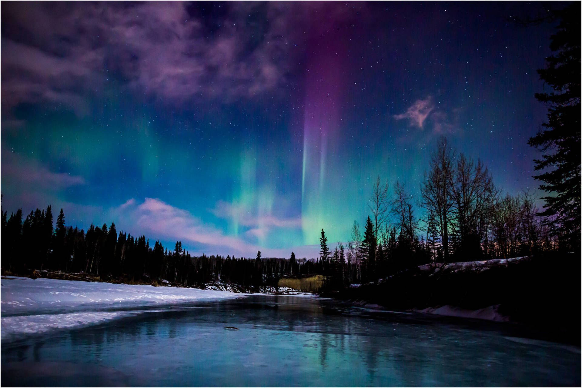 北極光照亮夜晚的雪森林河流，上方有星星。