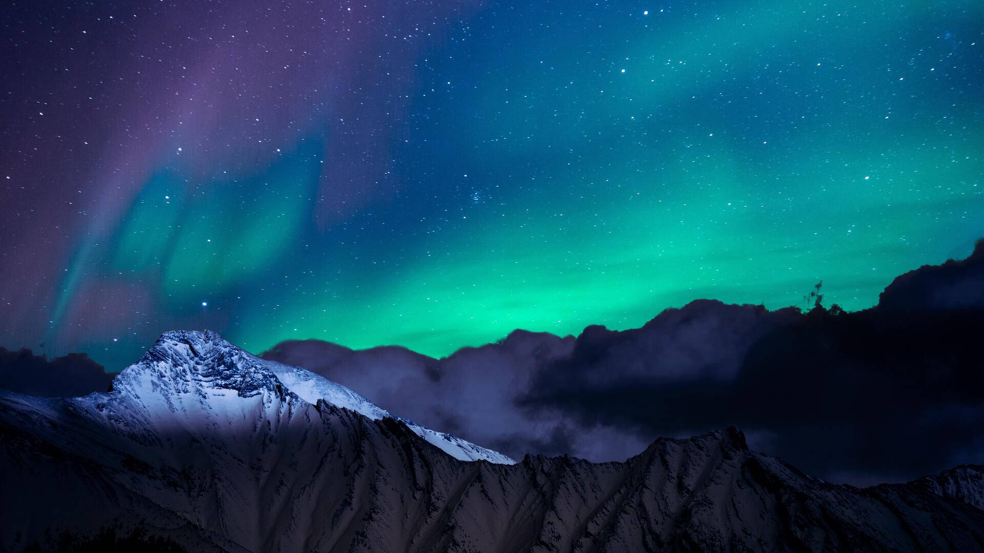 北極光在星空下在白雪覆蓋的山上發光。