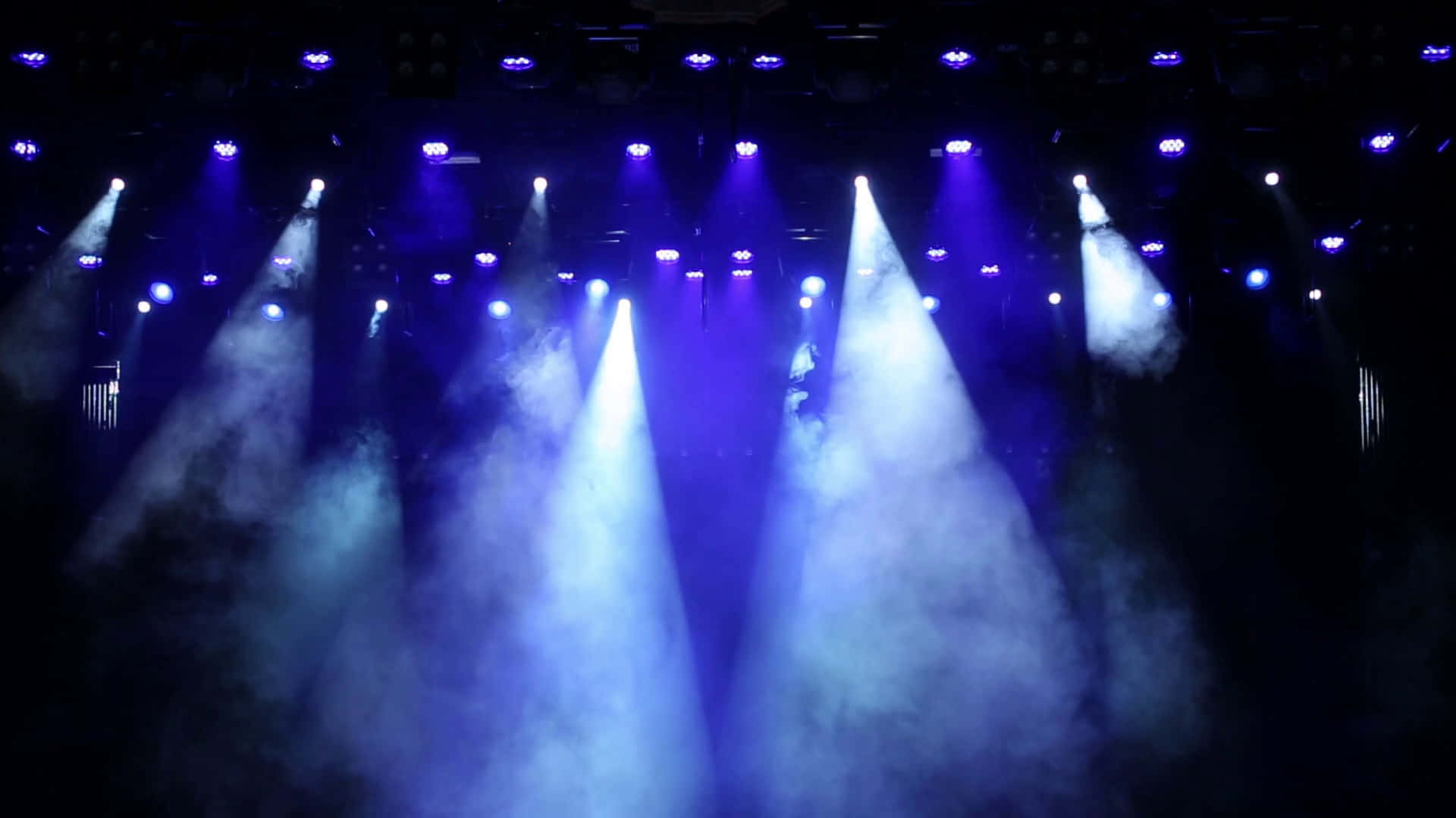 藍色舞台燈光在黑暗場地中穿過霧氣。