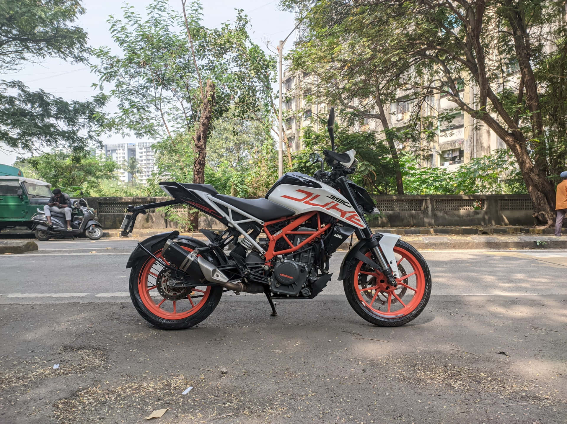一輛KTM Duke電單車停放在城市街道上，背景有樹木和建築物。