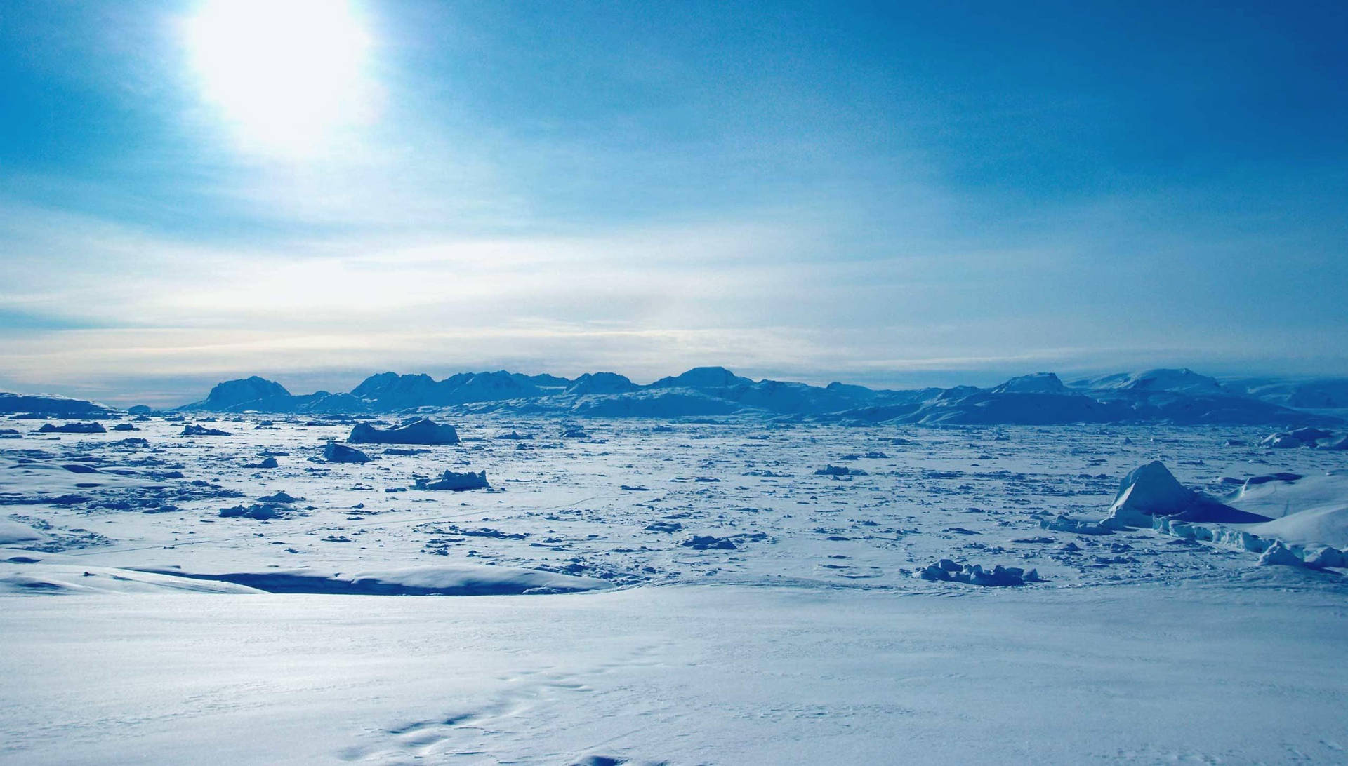 令人驚嘆的極地景觀，白雪覆蓋的冰面和遠山在明亮的陽光下。