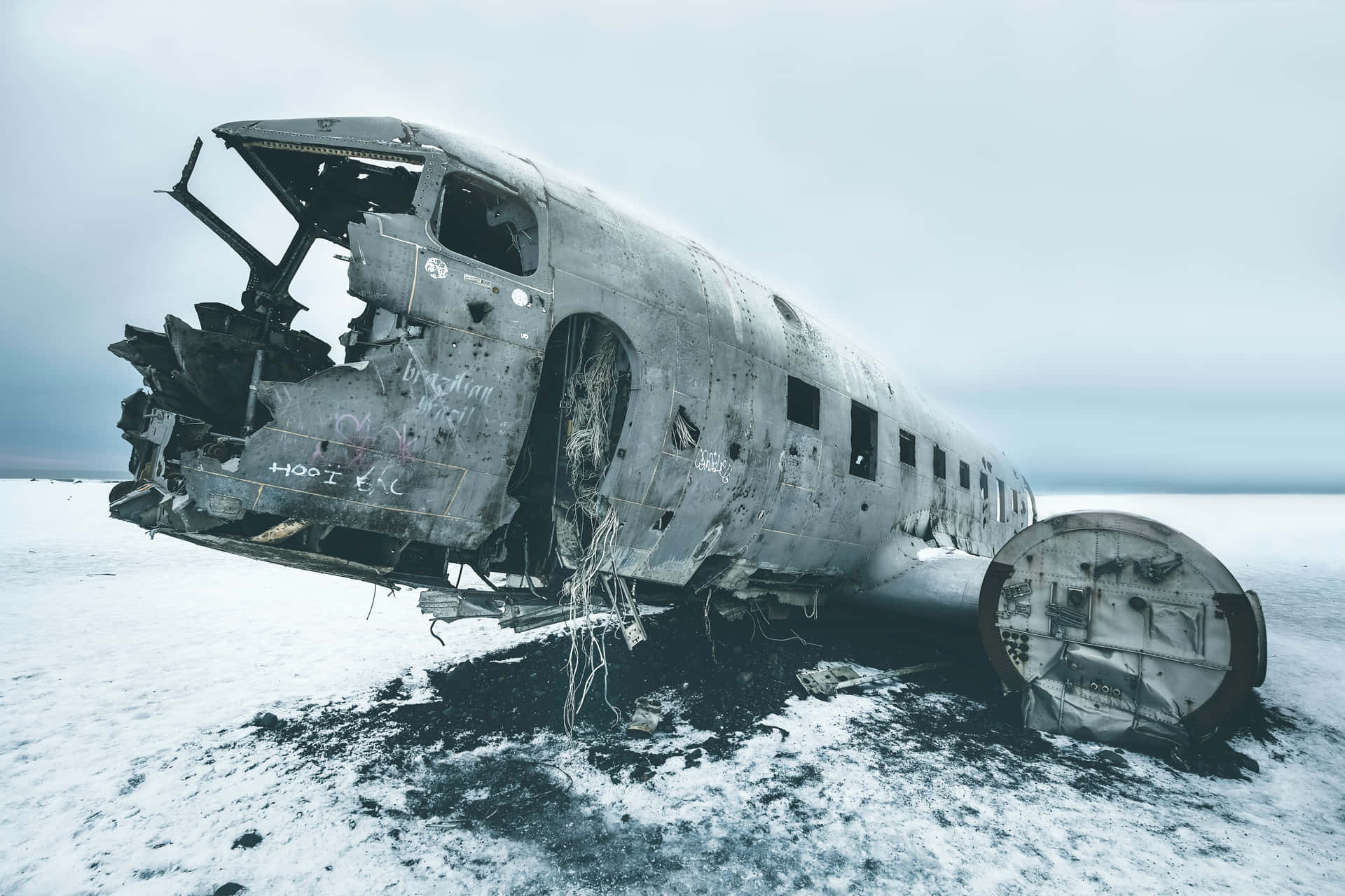 雪地上被遺棄的生鏽飛機殘骸，灰色天空
