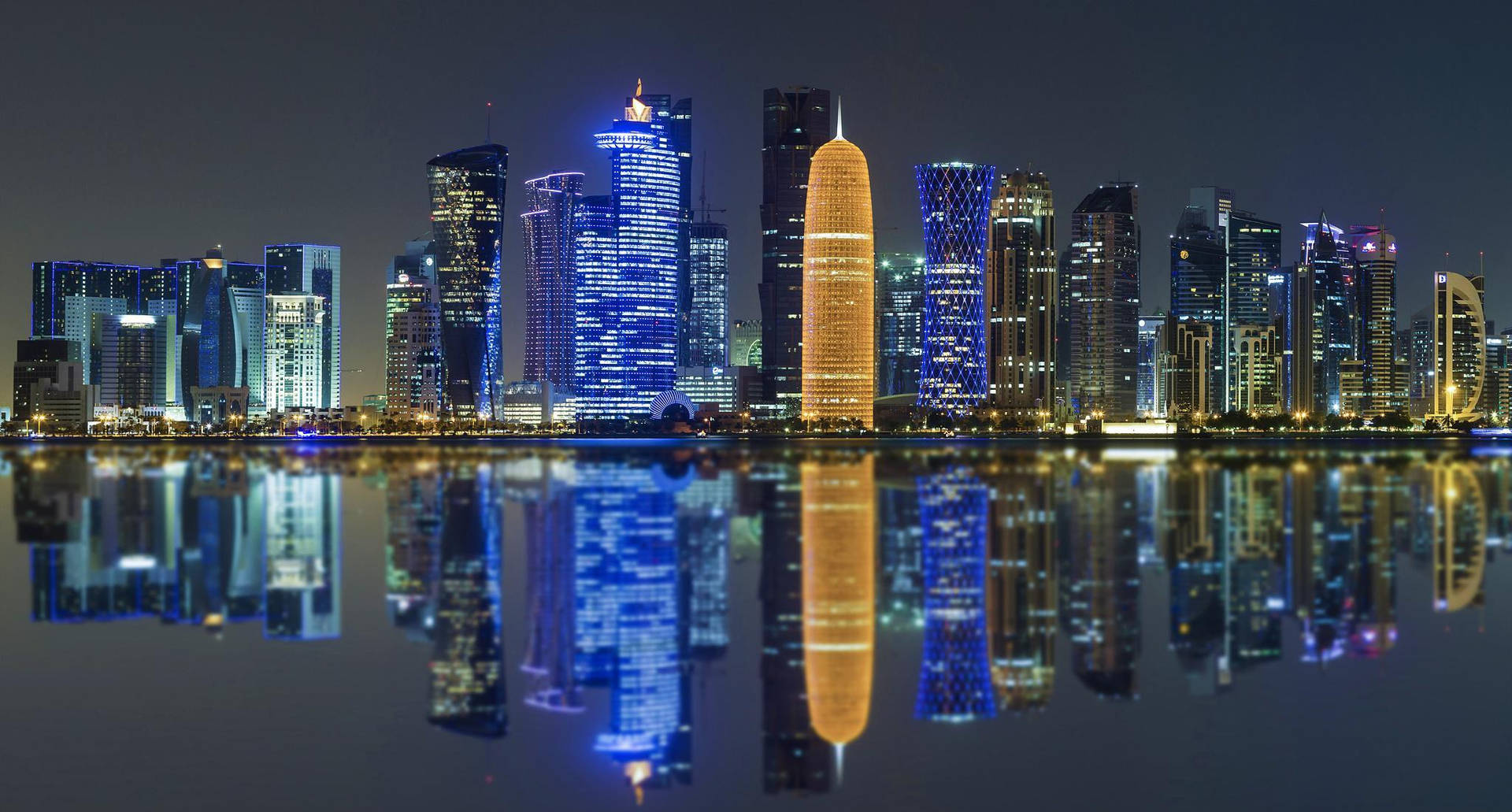 燈火通明的摩天大樓夜景倒映在平靜的水面上。