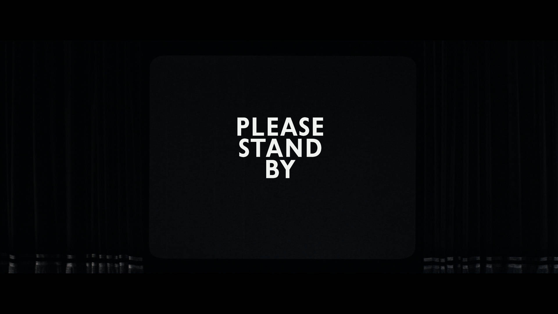 一個黑色電視屏幕，白色文字寫著「PLEASE STAND BY」，並可見靜電噪聲。