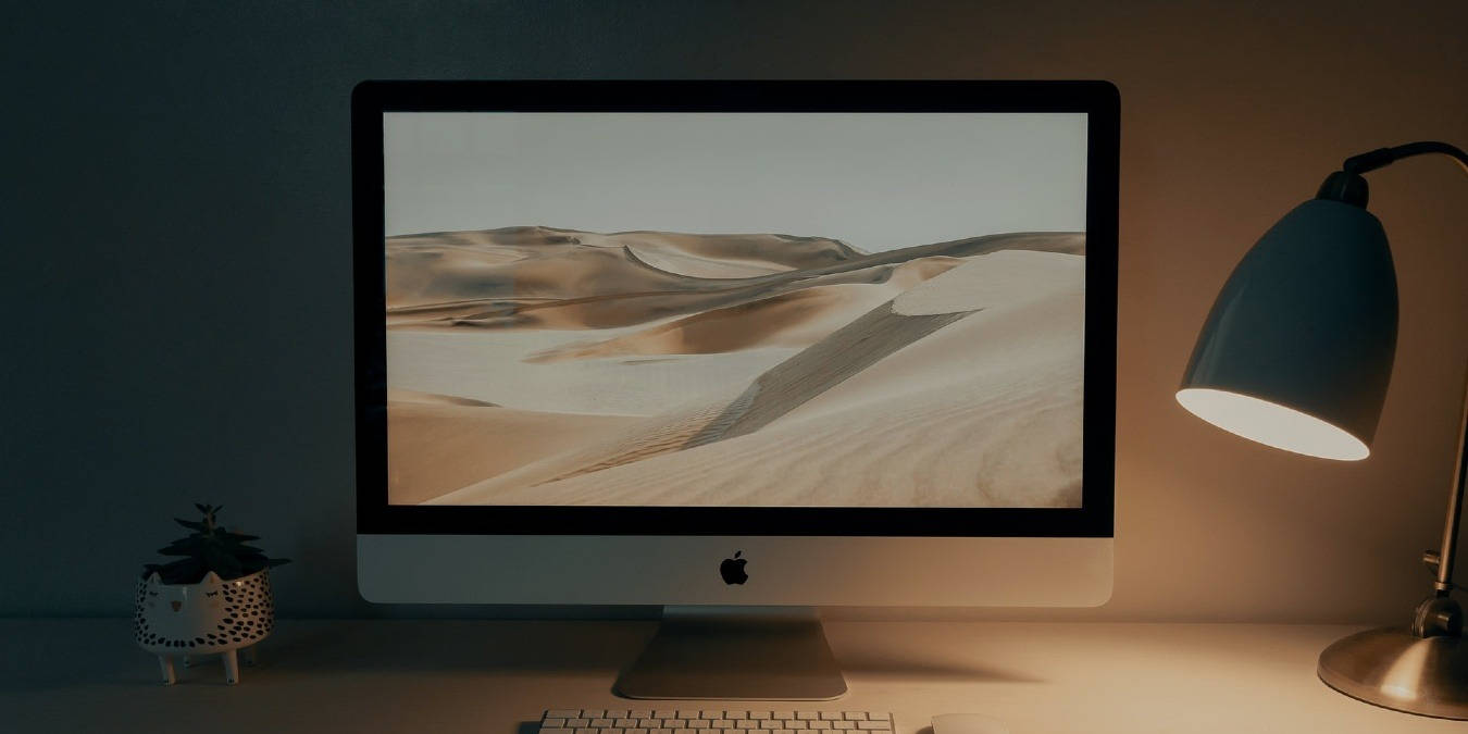 桌上的iMac，配有溫暖燈光和植物照亮的沙漠壁紙