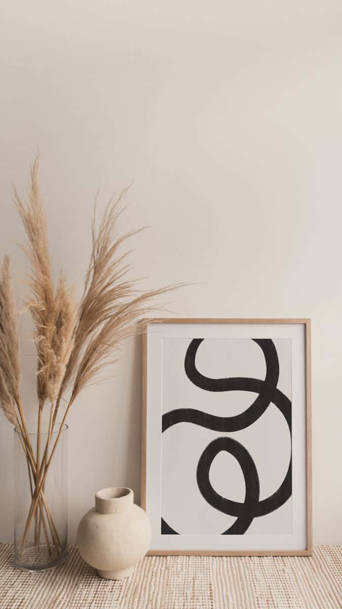Minimalist Painting 桌布 壁紙 — 極簡米色牆飾，搭配抽象黑色線條藝術畫框，旁邊擺放乾燥蒲葦和陶瓷花瓶。