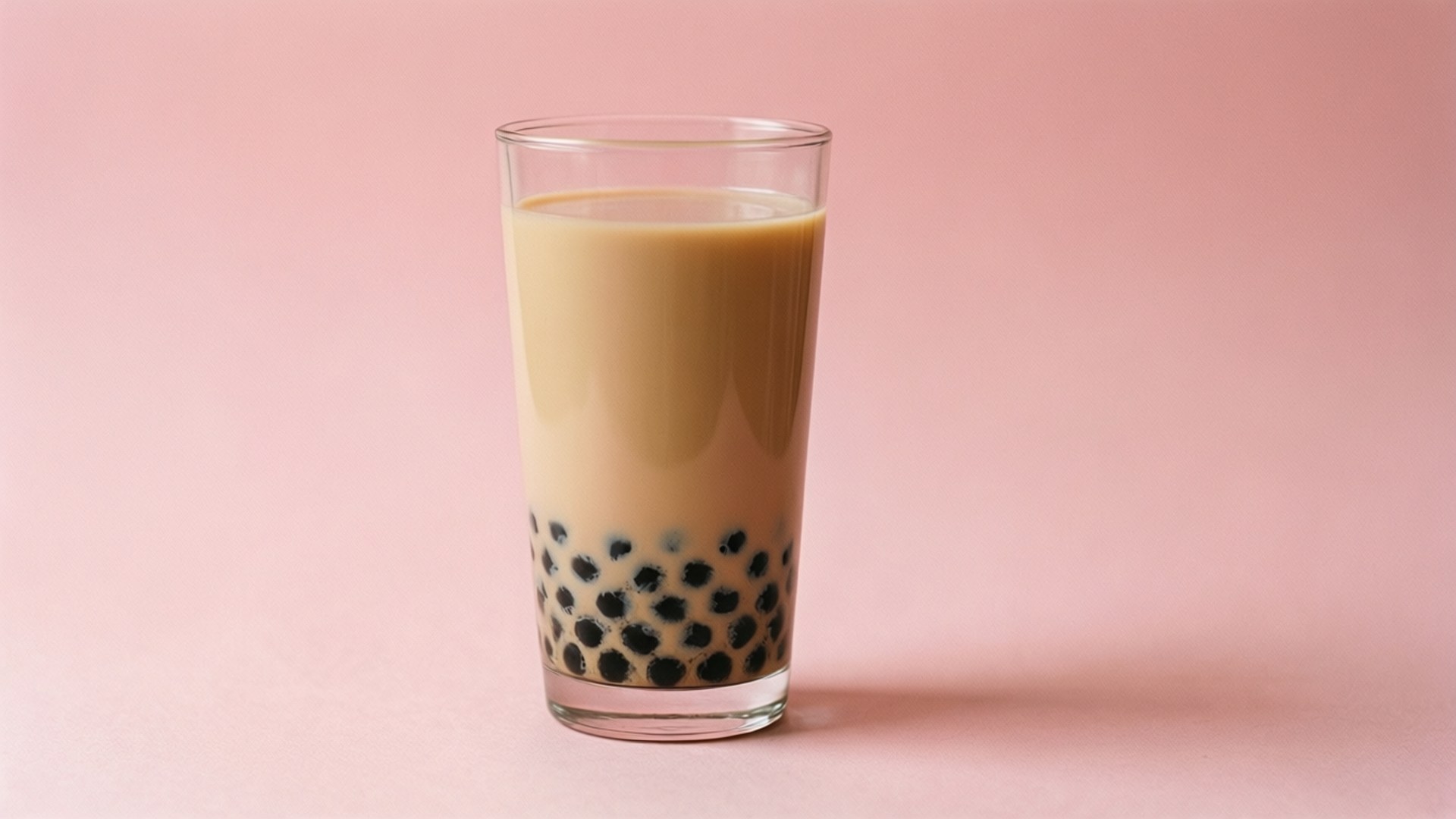 一杯珍珠奶茶，黑色珍珠喺粉紅色表面上