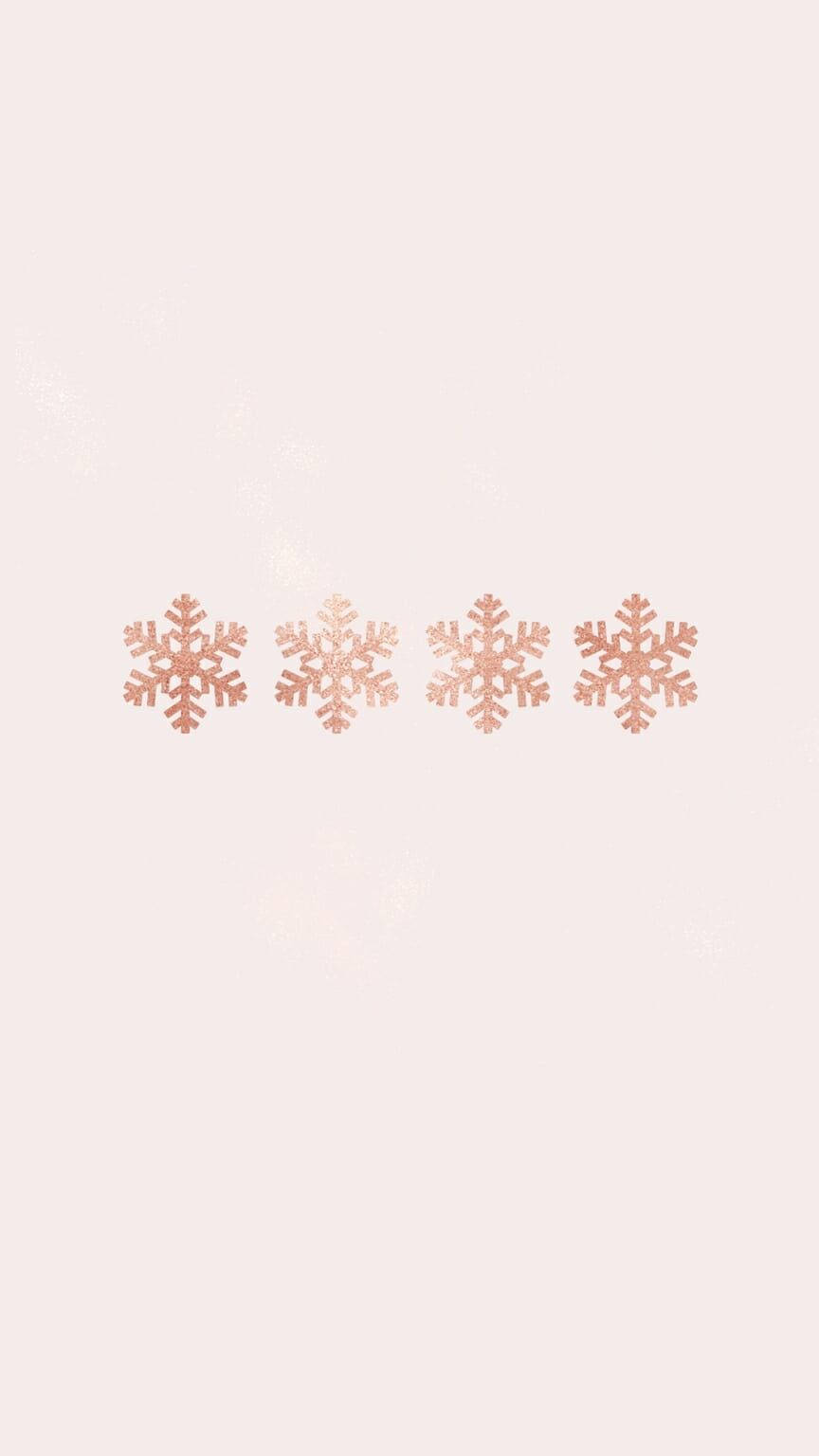 極簡雪花聖誕手機壁紙 壁紙 — 四朵玫瑰金色雪花在柔和的胭脂色背景上輕輕飄浮，帶有微妙的閃亮雪花點綴。