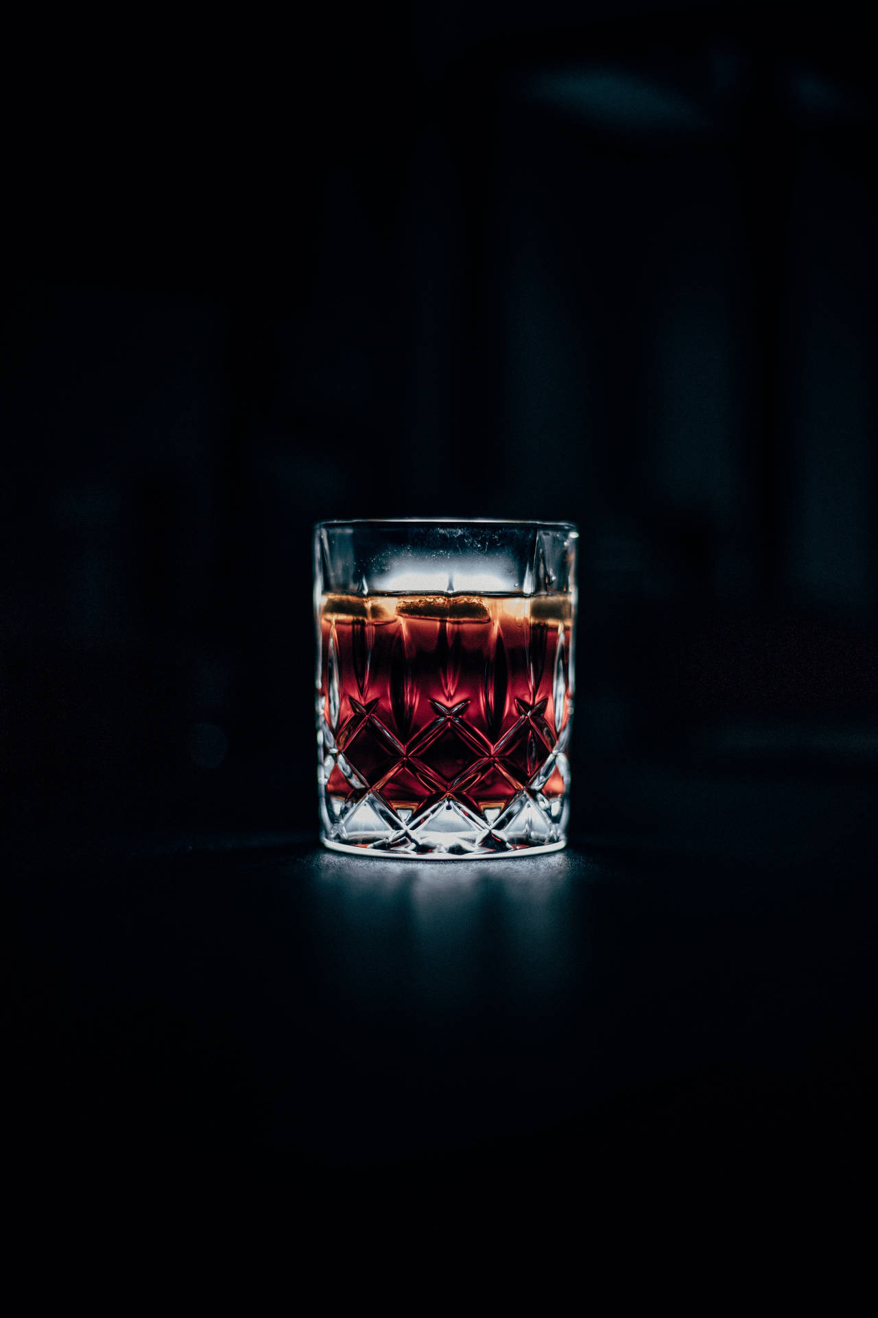 一個在黑暗中發光、帶冰塊的水晶威士忌杯