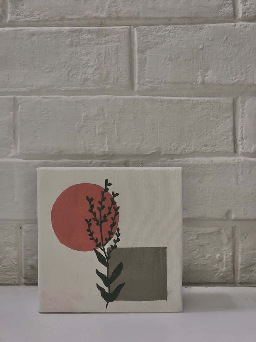 Minimalist Painting 桌布 壁紙 — 極簡風格帆布畫，灰色正方形背景上有一個紅色圓圈和黑色植物剪影，靠在一面白色磚牆上。