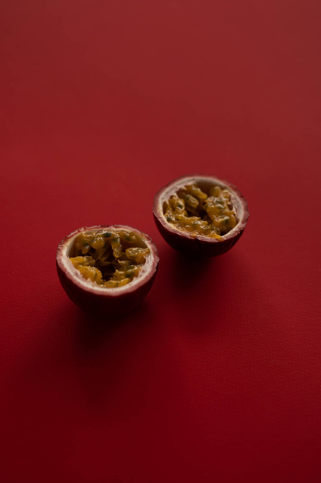 兩個切半的熱情果放在紅色表面上。