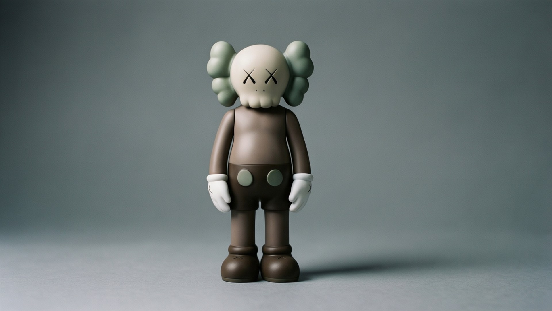 極簡風格的Kaws BFF 壁紙 — AKA kaws 人偶居中站立於柔和灰色背景前，柔和的工作室燈光突顯其光滑的啞光質感。