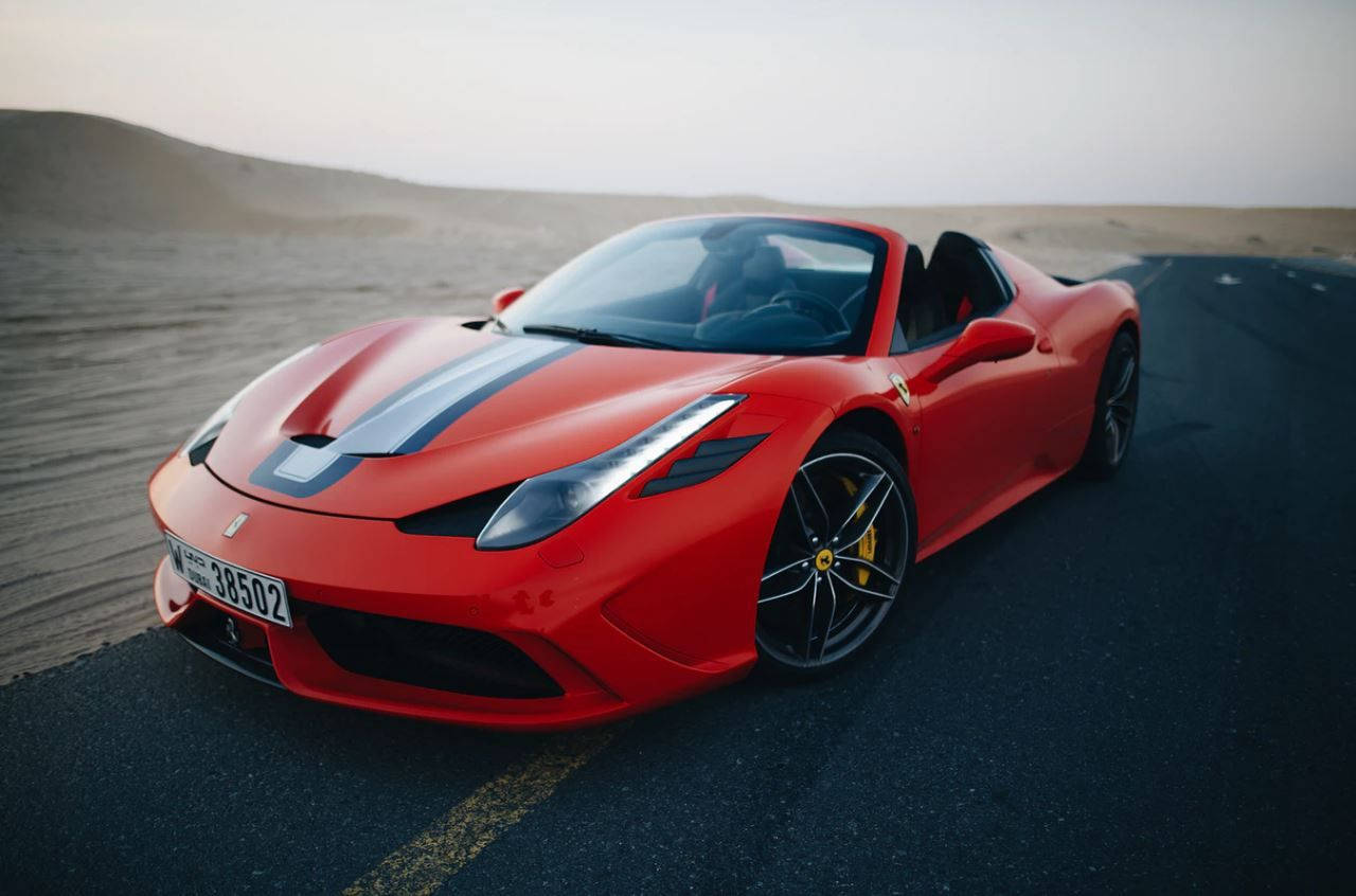 極致酷炫跑車 Ferrari Speciale 壁紙 — 一輛鮮紅色法拉利跑車帶有黑色賽車條紋，在黎明時分沿沙漠公路行駛。