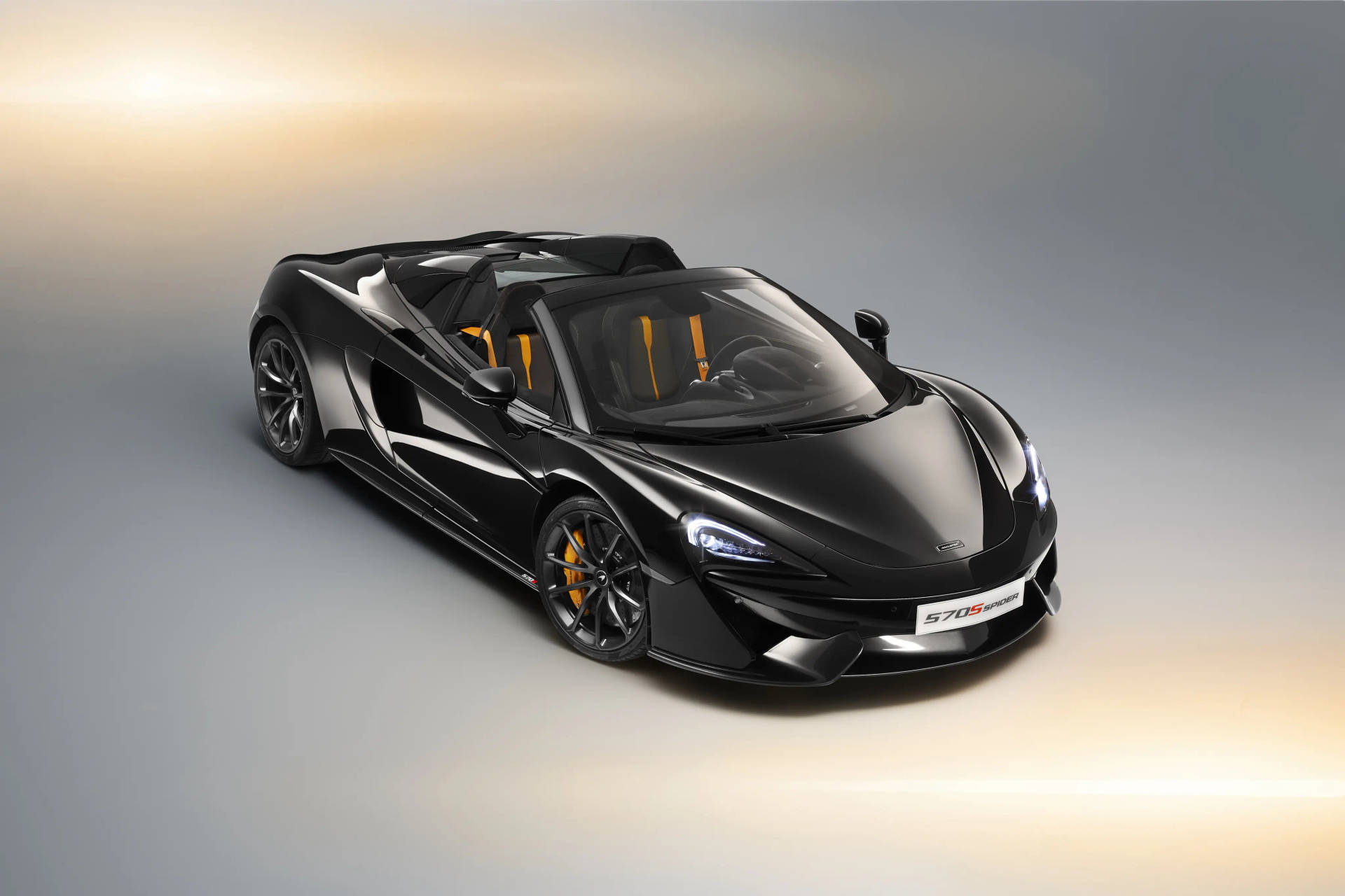 黑色McLaren 570S Spider，配橙色內飾及車頭燈亮起。