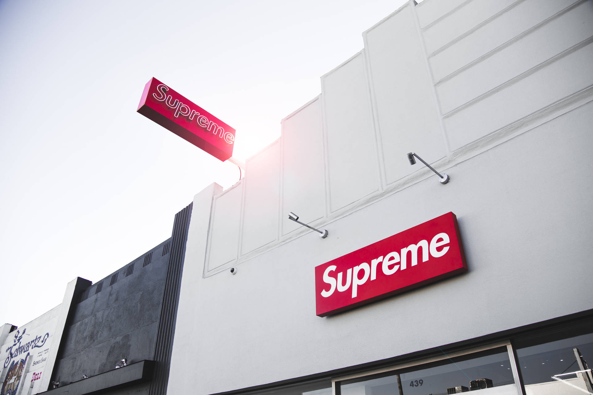 日落時分，白色建築上帶有紅色標誌的Supreme品牌商店。