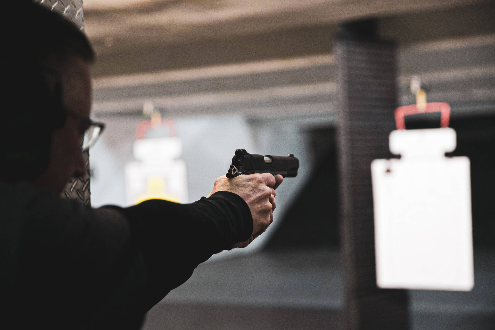 在室內射擊場用手槍瞄準靶子的人士
