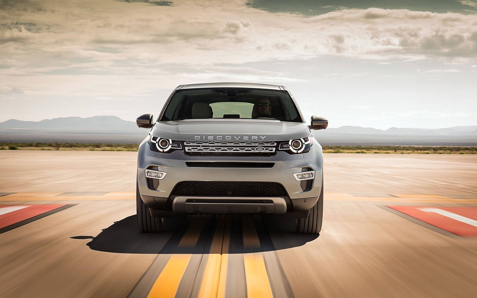 銀色 Land Rover Discovery 在沙漠賽道上疾馳，帶有模糊運動。