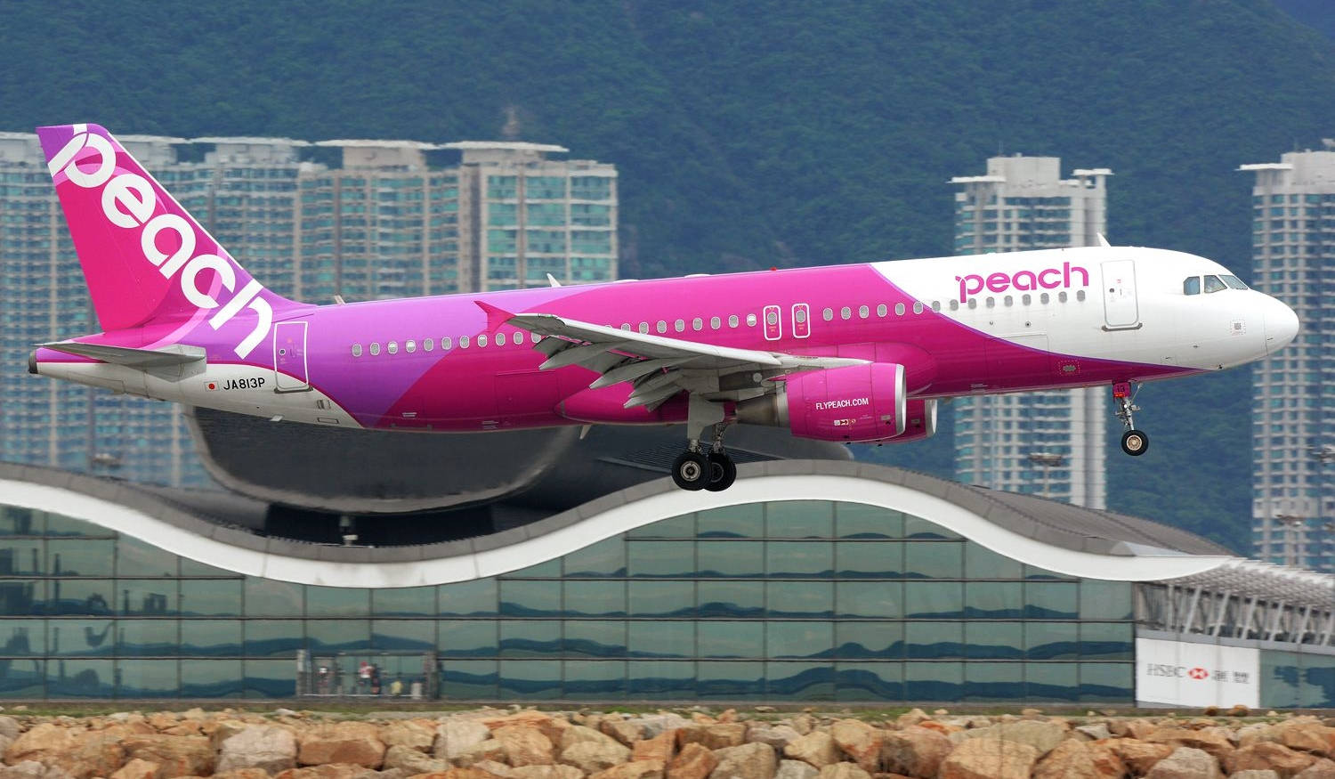 粉紅色Peach Airlines飛機從機場航站樓爬升。