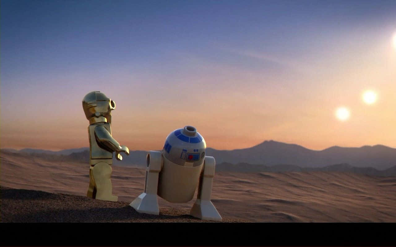 Cool Star Wars 桌布 壁紙 — 樂高C-3PO和R2-D2站在沙漠星球上，夕陽西下，天空中有兩個太陽發光。