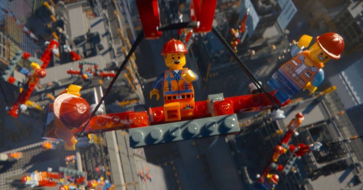 《樂高大電影》建設場景精彩劇照 壁紙 — 兩名微笑的LEGO建築工人從紅色起重機上懸掛在下方繁忙的LEGO城市景觀之上。