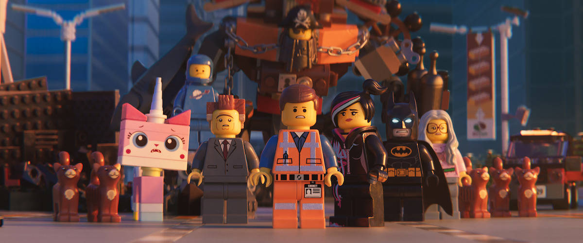 《樂高大電影》與商界大魔王 壁紙 — 一組LEGO角色，包括蝙蝠俠和獨角貓，在日落時分的風格化城市景觀中站在一起。