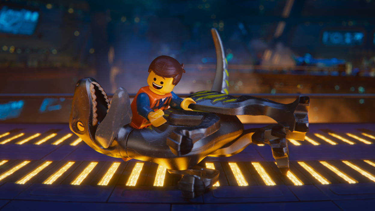 《樂高大電影2》恐龍場景 壁紙 — 一個微笑的LEGO迷你人偶在夜晚霓虹燈閃爍的城市景觀中，騎著一輛未來主義的鯊魚形車輛，行駛在發光的黃色平台上。