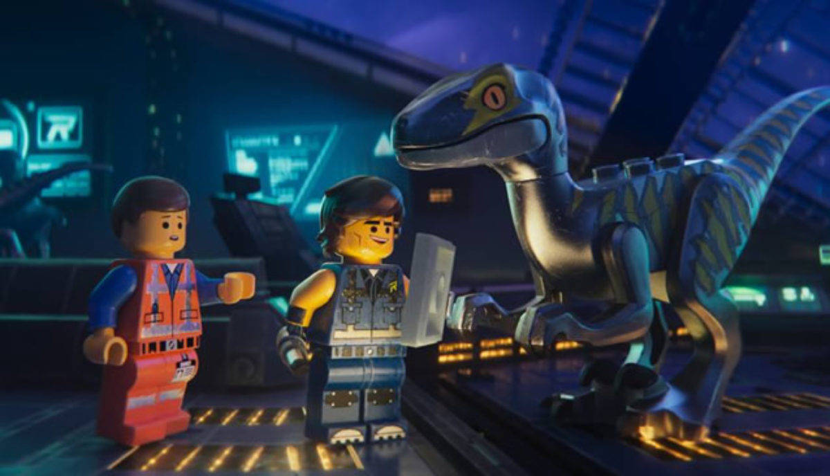 《樂高大電影2》恐龍場景 壁紙 — 兩個LEGO角色站在一個高科技控制室中，旁邊有一隻大型LEGO恐龍，在發光的藍色燈光下。
