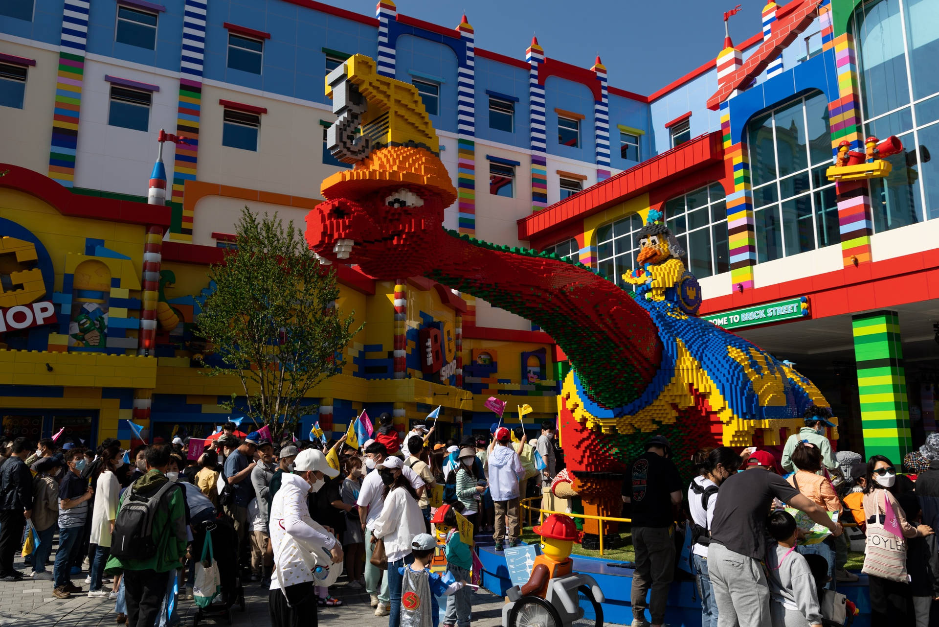 人們在LEGO主題公園聚集在一個巨大的LEGO恐龍雕塑周圍。