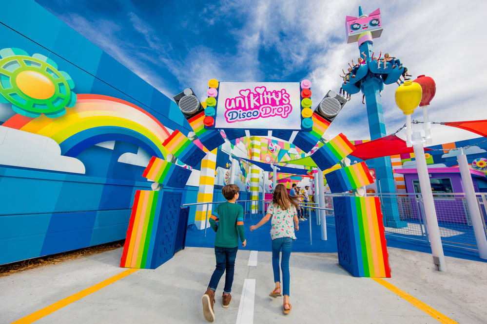 兩個孩子向住色彩繽紛嘅Unikitty's Disco Drop遊樂設施入口行去。
