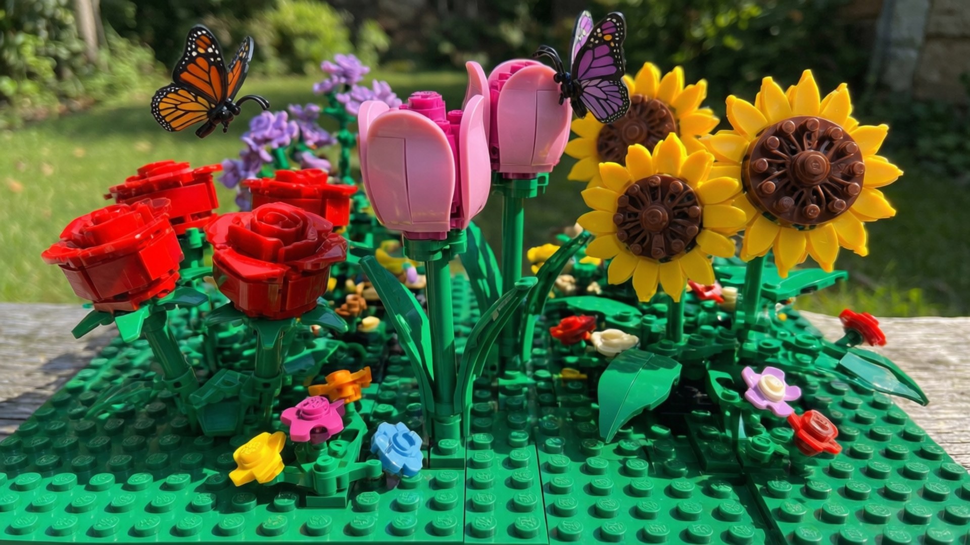 綠色底板上的花園場景中的LEGO花朵和蝴蝶。