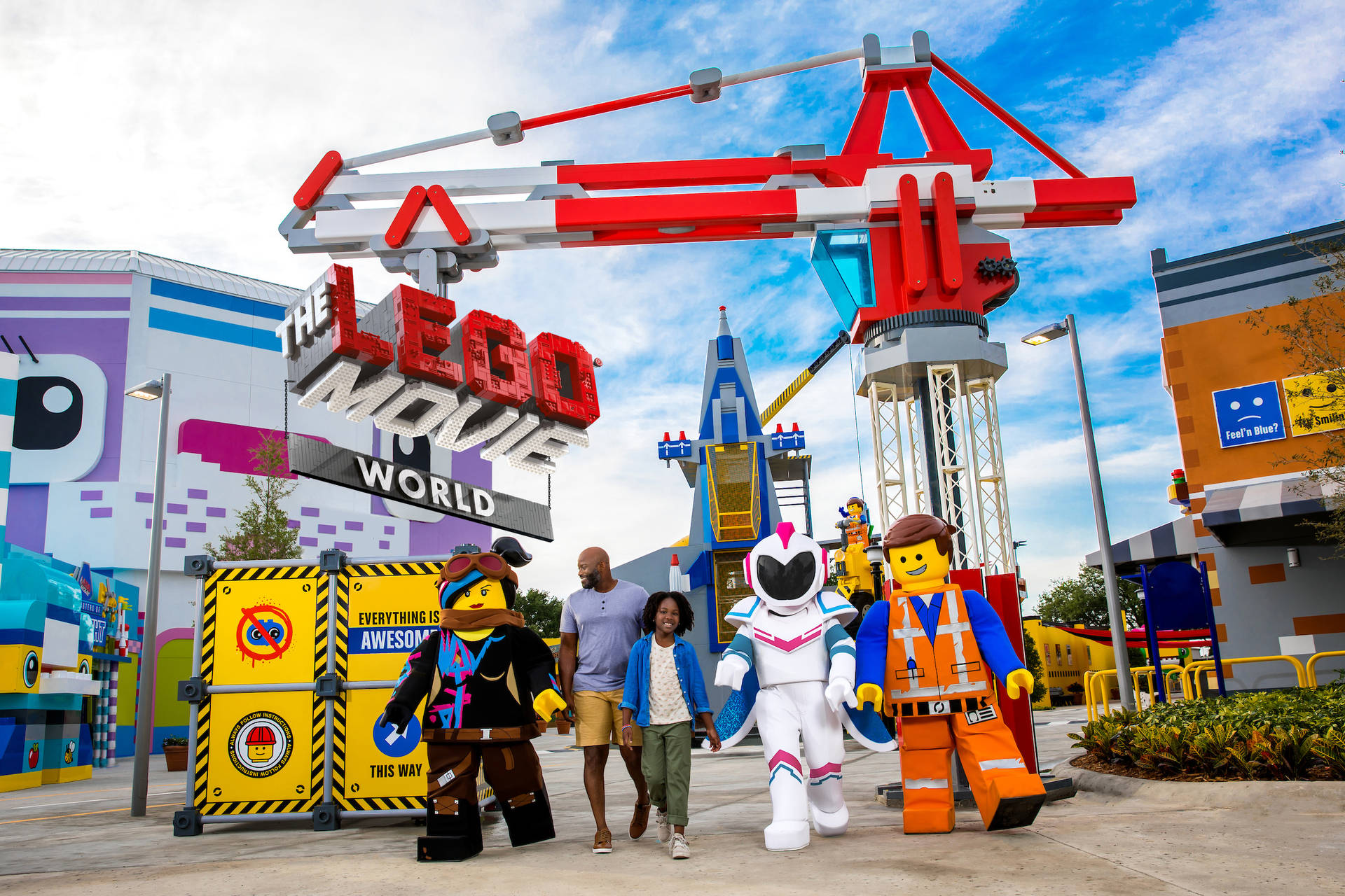家庭與LEGO Movie角色在主題公園入口散步。