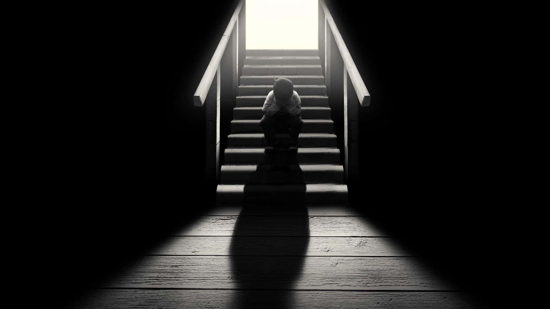 樓梯下的憂鬱少年 壁紙 — 一個孤獨的身影蜷縮在樓梯底部，被上方刺眼的光線照亮，在木地板上投下長長的影子。