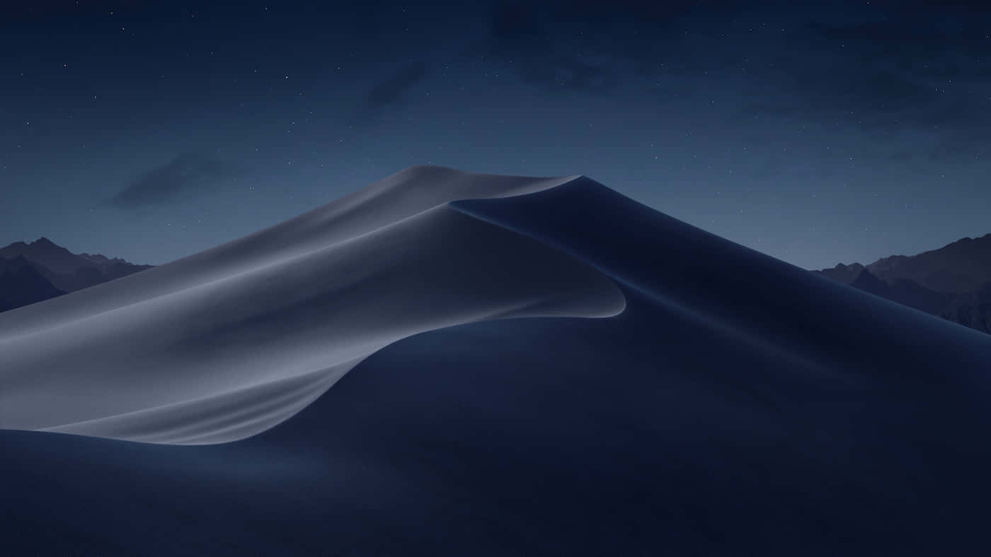 標準 Mac 沙漠首頁背景 壁紙 — 一個寧靜的夜晚場景，平滑起伏的沙丘在星空下，遠方有山脈。