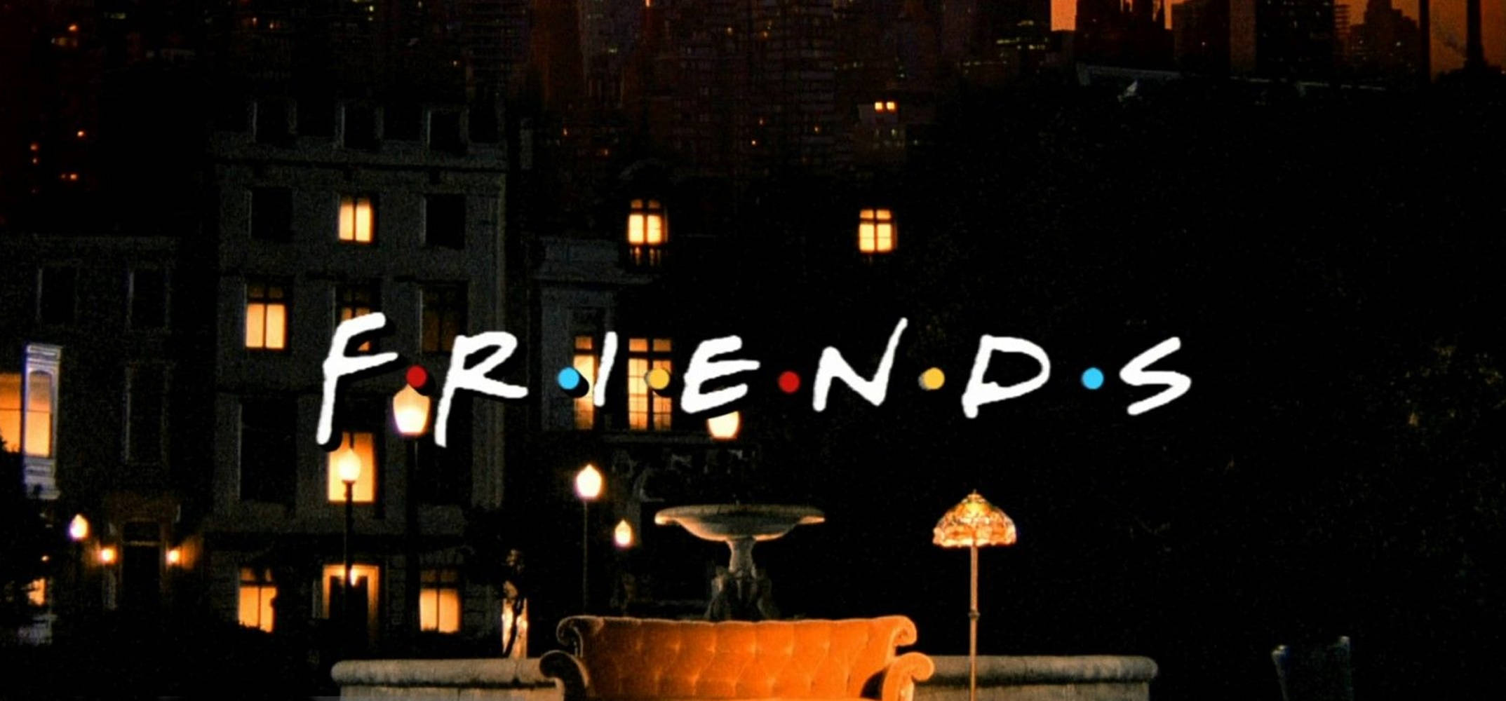Friends Logo 桌布 壁紙 — 標誌性的《老友記》標誌在夜間城市景觀中發光，窗戶溫暖明亮，屋頂上有一張沙發。