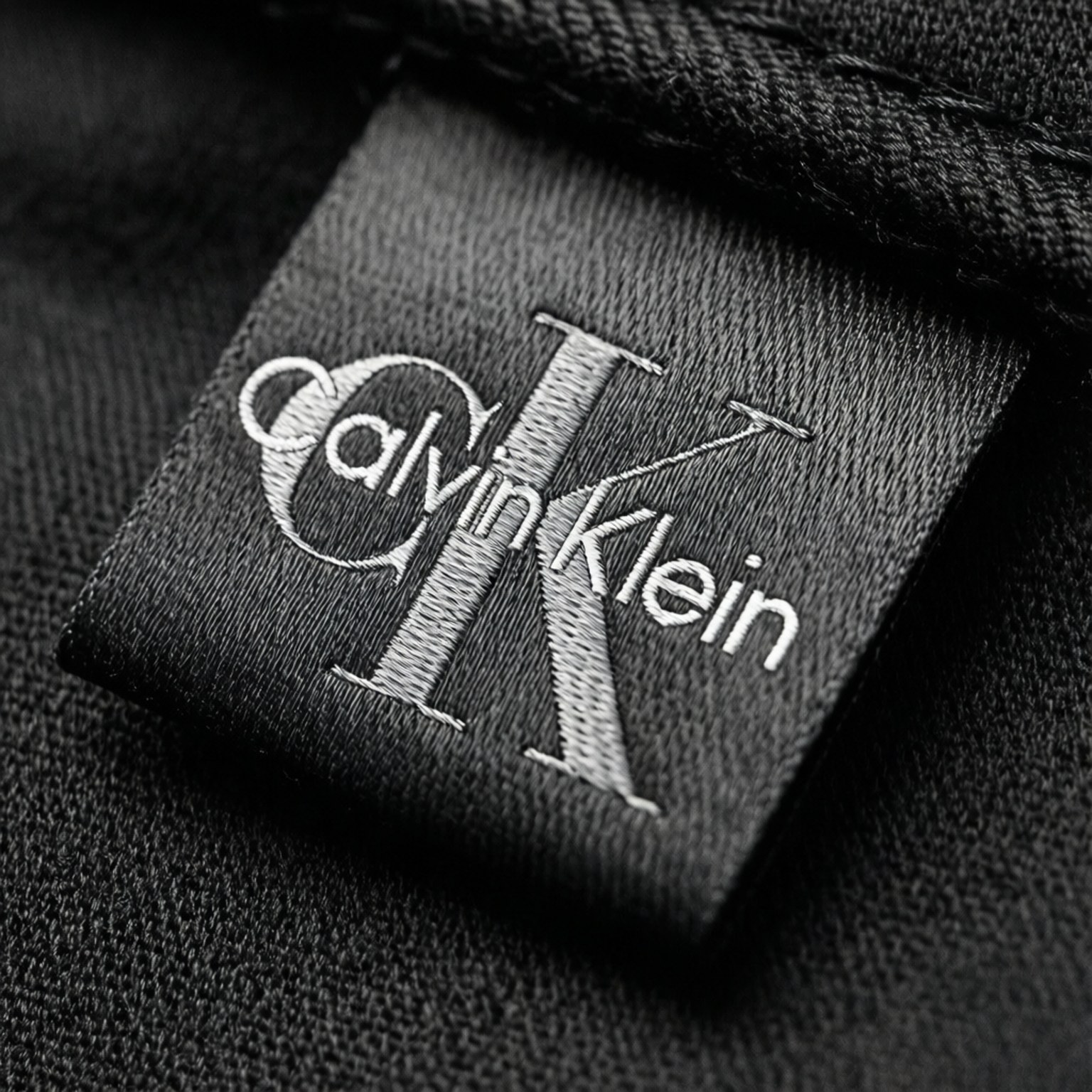 Calvin Klein服裝品牌標籤特寫，黑色布料上有白色縫線。